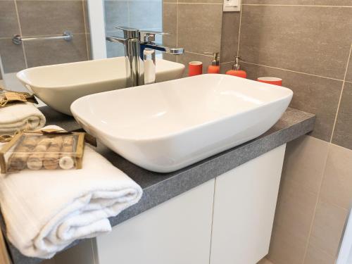 La salle de bains est pourvue d'un lavabo blanc sur un comptoir. dans l'établissement Parco del Mare - Relax near the sea and city centre, à Borghetto Santo Spirito