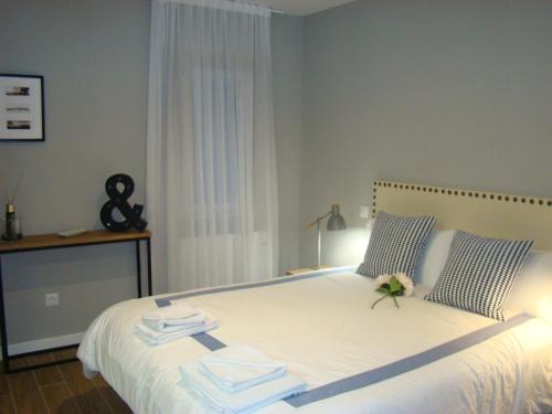 Un dormitorio con una gran cama blanca con una flor. en Apartamentos La Pereda Santander- Estudio E1, en Santander