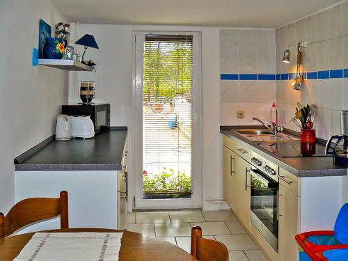 eine Küche mit einem Tisch, einem Waschbecken und einem Fenster in der Unterkunft Ferienwohnungen Sylvia in Prohn