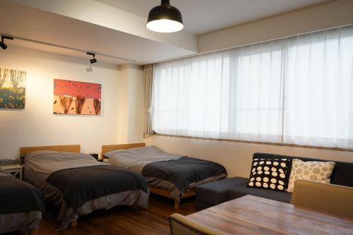 um quarto com duas camas e uma mesa e uma janela em Culinary Bed&Art 404 em Hamamatsu