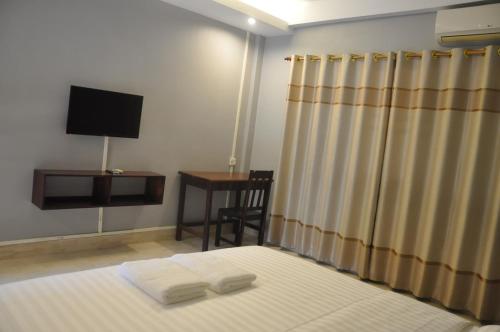 a bedroom with a bed with a television and a desk at Pilgrim's Kitchen & Inn in Savannakhet