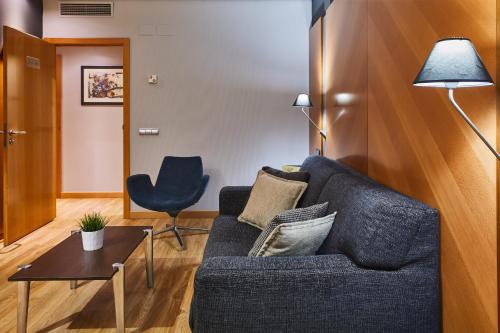 a living room with a blue couch and a chair at Silken Juan de Austria in Valladolid