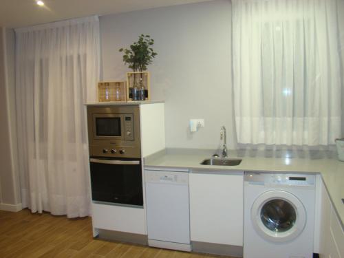 a kitchen with a washing machine and a microwave at Apartamentos LA PEREDA SANTANDER in Santander