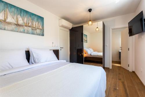 1 dormitorio con 1 cama blanca y TV en Villa Manhattan en Dobrinj