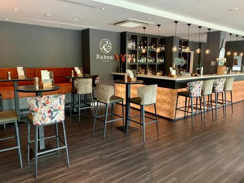 a bar in a restaurant with bar stools at Tulip Inn Leiden Centre in Leiden