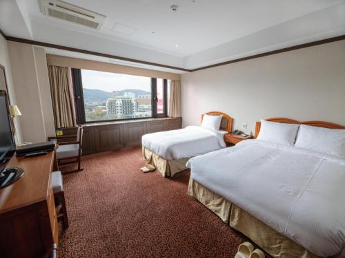 a hotel room with two beds and a large window at The K Hotel Gyeongju in Gyeongju