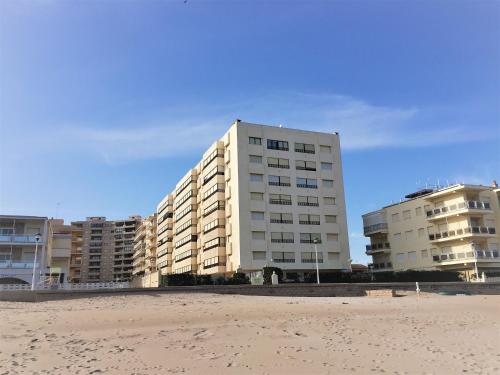 a tall building on the beach next to the sand at Cozy Apartment in a Beachfront Complex in Mareny Blau