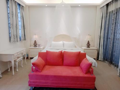 um quarto com um sofá vermelho em frente a uma cama em 一中太陽綠墅 em Taichung