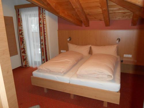 1 cama con sábanas blancas y almohadas en una habitación en Appartement beim Brunnen 10, en Sölden