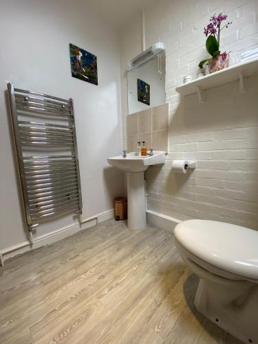 a white bathroom with a sink and a toilet at Kirkdale Cottage in Helmsley