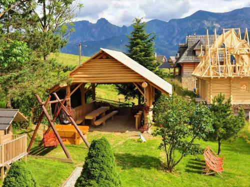 a small wooden house with a playground in a yard at Noclegi u Gabrysi in Kościelisko
