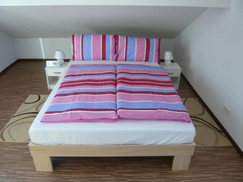 a bed with pink and blue striped sheets in a room at Am Moos in Isny im Allgäu