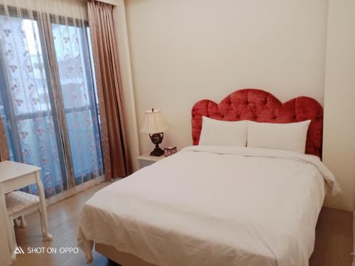 a bedroom with a large bed with a red headboard at 一中太陽綠墅 in Taichung