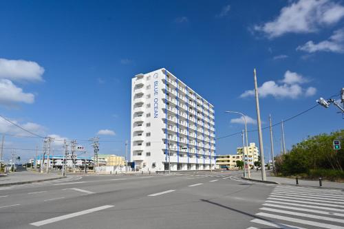 a tall white building on the side of a street at Daily & Weekly Condominium BLUE OCEAN ISHIGAKI in Ishigaki Island