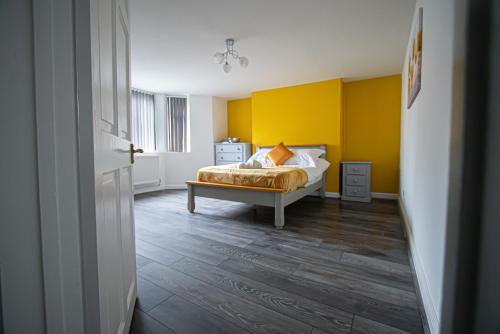 a bedroom with a bed and a yellow wall at Clarence Retreat in Newport