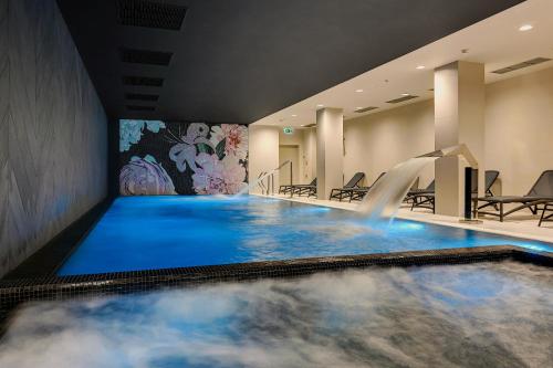 - une piscine avec cascade dans une chambre d'hôtel dans l'établissement GRANO APARTMENTS Gdańsk Old Town SPA & Wellness, à Gdańsk