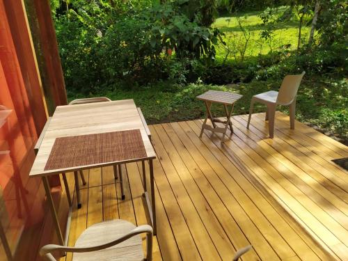 a wooden deck with a table and chairs on it at Mindo Eco Suite con Rio y Cascada in Mindo