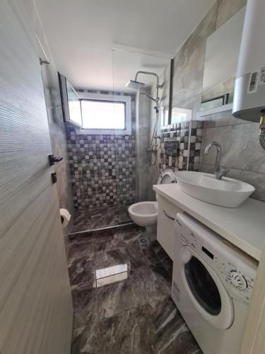 a bathroom with a sink and a washing machine at Apartments Nera Paralia-Apartment with sea view in Paralia Katerinis