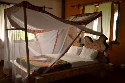 a bedroom with a canopy bed with white curtains at Topi Lodge in Queen Elizabeth National Park