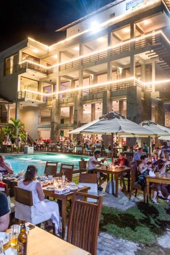 a group of people sitting at tables in front of a pool at Paradise Beach Club in Mirissa