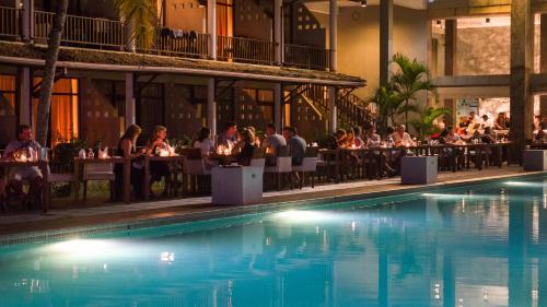 a group of people sitting at tables by a swimming pool at Paradise Beach Club in Mirissa