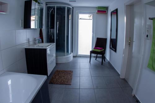 ein Badezimmer mit einem Waschbecken, einer Dusche und einem Stuhl in der Unterkunft Ferienhaus Deko-Scheune in Naila