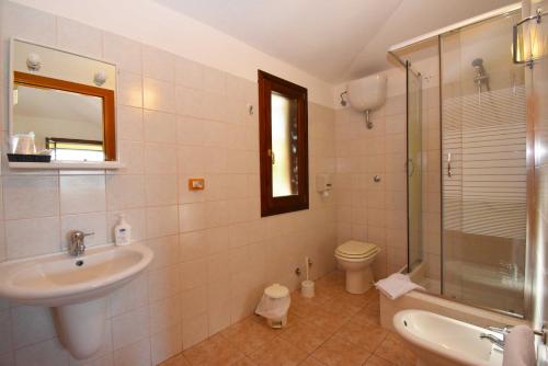 a bathroom with a sink and a toilet and a mirror at La Corte Degli Ulivi in Cardedu