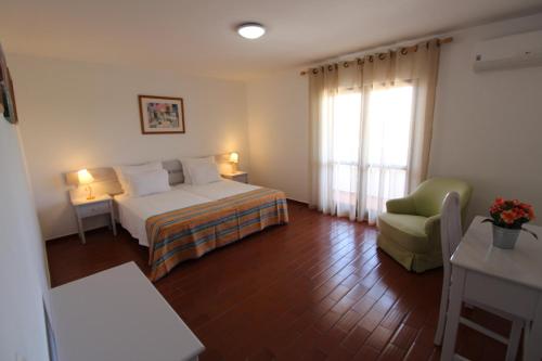 Pokój hotelowy z łóżkiem i krzesłem w obiekcie Balaia Sol Holiday Club w Albufeirze