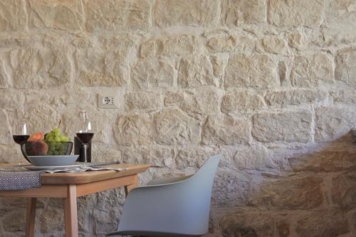 a table with a chair and a stone wall at Locanda Angelica in Giarratana