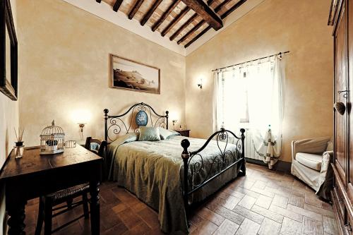 a bedroom with a bed and a desk and a window at Agriturismo Il Casalino in Pienza