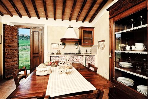a dining room with a table and a kitchen at Agriturismo Il Casalino in Pienza