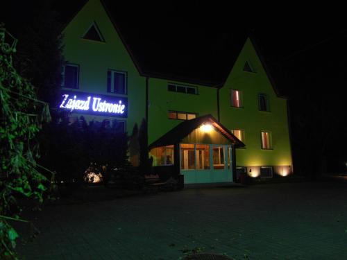 a green building with a blue sign on it at night at Zajazd Ustronie in Piaseczno