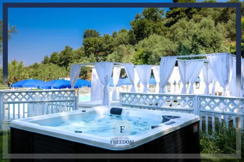 a jacuzzi tub on a patio with white curtains at Hotel & Spa Relais Freedom Club in Massa Lubrense