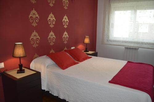 a bedroom with a bed with red walls and two lamps at Apartamento con vistas en Cambados in Cambados