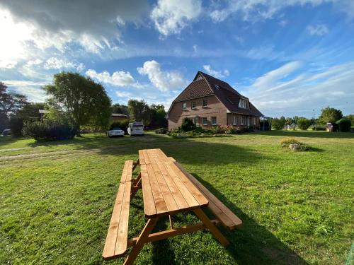 a wooden picnic table in a field with a house at Tom's Hof in Dierhagen