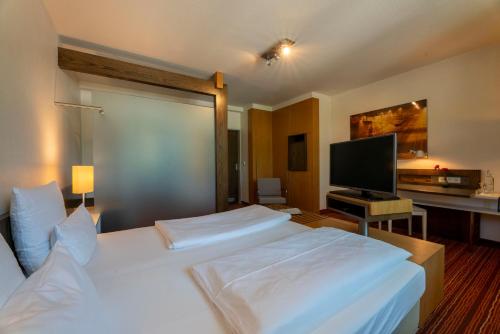 a bedroom with a large white bed and a flat screen tv at Hotel An der Gruga in Essen