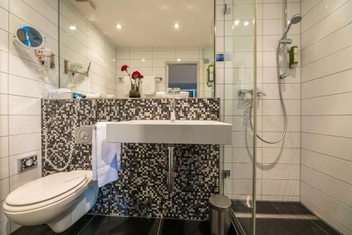e bagno con servizi igienici, lavandino e doccia. di Hotel An der Gruga a Essen