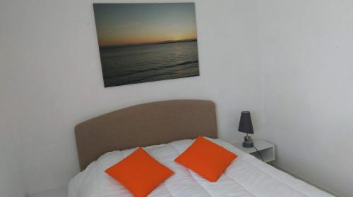 a bedroom with a bed with orange pillows on it at À moins de 100 mètres de la mer a la pointe de Trevignon in Trégunc