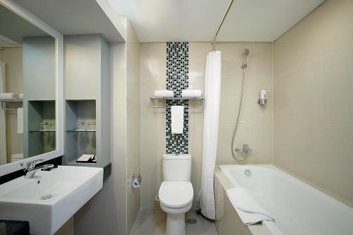 ein Badezimmer mit einem WC, einem Waschbecken und einer Badewanne in der Unterkunft BATIQA Hotel & Apartments Karawang in Karawang