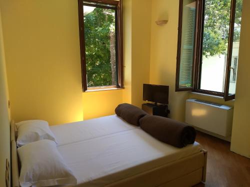 um quarto com uma grande cama branca e 2 janelas em Villa Luzzatti em Roma
