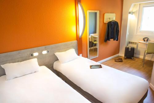 a bedroom with two beds with orange walls and a mirror at ibis budget Vienne Sud in Vienne