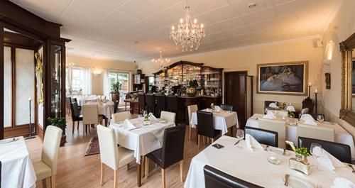 a restaurant with white tables and chairs and a chandelier at Residenz Royal in Sandhausen