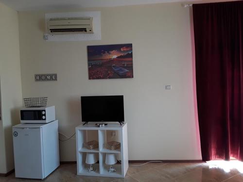 a living room with a television and a small refrigerator at SUNNY SEA PALACE 502 Studio Sunny Beach in Sunny Beach