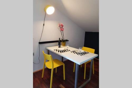 einen Esstisch mit gelben Stühlen und einer Lampe in der Unterkunft Cozy loft in Rijeka