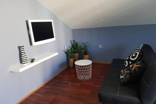 un soggiorno con divano nero e TV di Cozy loft a Fiume (Rijeka)