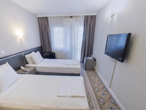 a hotel room with two beds and a flat screen tv at Hotel Balca in Izmir