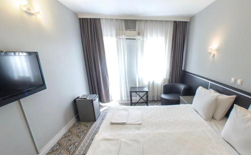 a hotel room with a bed and a flat screen tv at Hotel Balca in Izmir