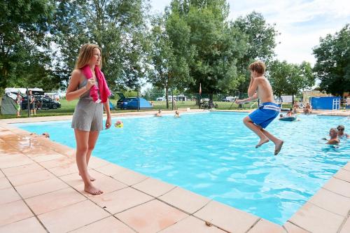 une femme debout à côté d'un garçon dans une piscine dans l'établissement Camping Aux Rives du Soleil, à Pont-de-Vaux