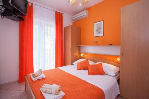 a bedroom with a bed with orange walls and a television at Pansion Burin in Baška