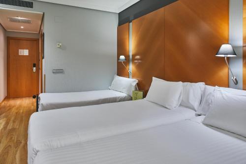 a hotel room with two beds with white sheets at Silken Juan de Austria in Valladolid